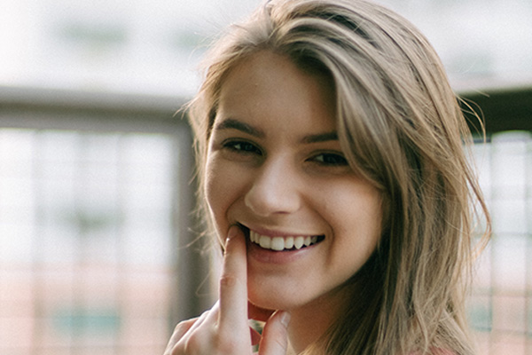 Girl smiling pointing at teeth, Dental Fees